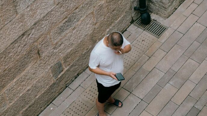 a man standing next to a wall talking on a cell phone