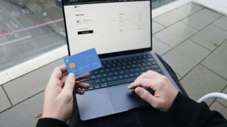 A person sitting in a chair with a laptop and a credit card