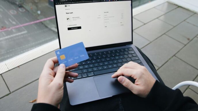 A person sitting in a chair with a laptop and a credit card
