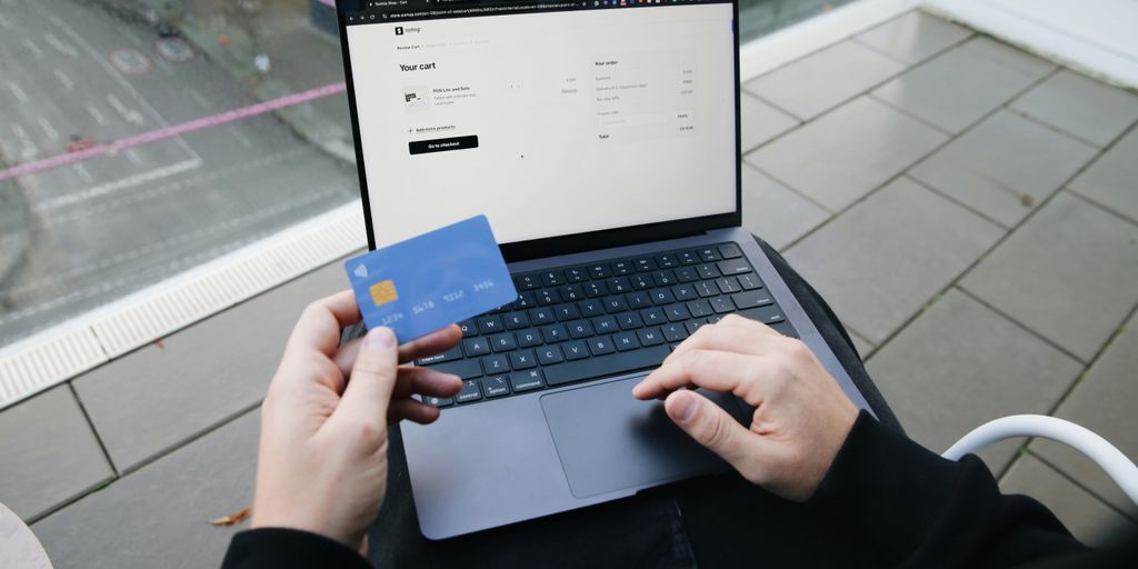 A person sitting in a chair with a laptop and a credit card