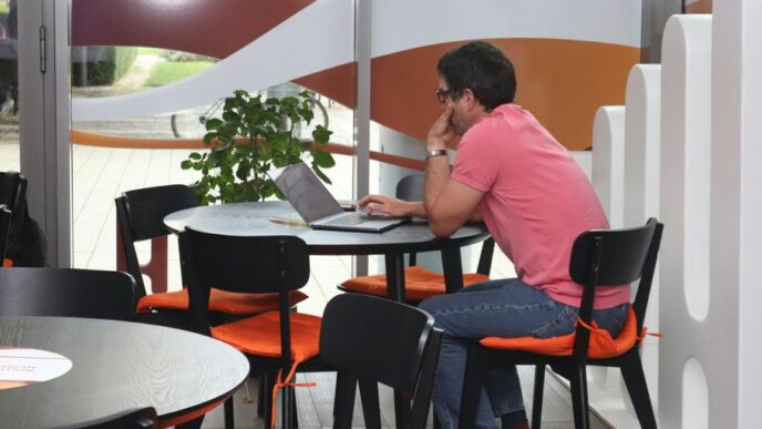 A man sitting at a table using a laptop computer