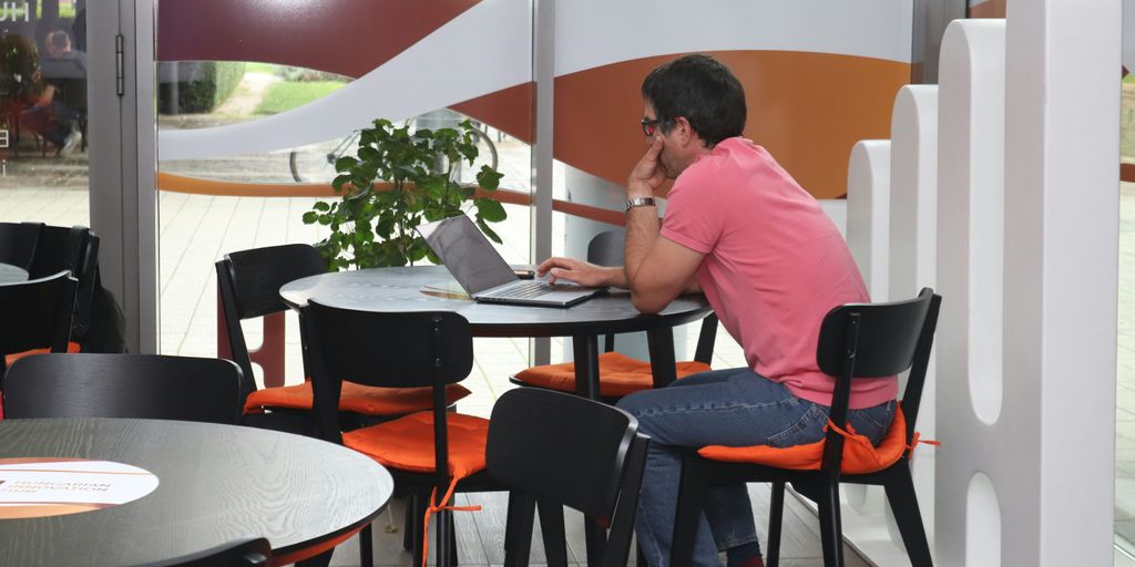 A man sitting at a table using a laptop computer