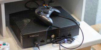 Here's a caption: an original xbox console with a controller.