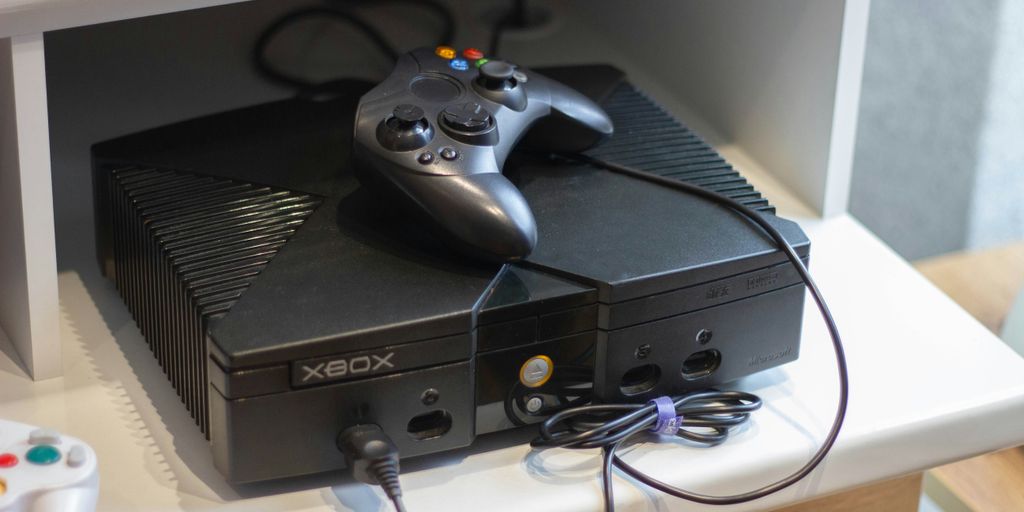 Here's a caption: an original xbox console with a controller.