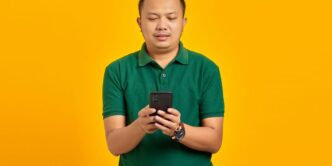 a man in a green shirt looking at a cell phone