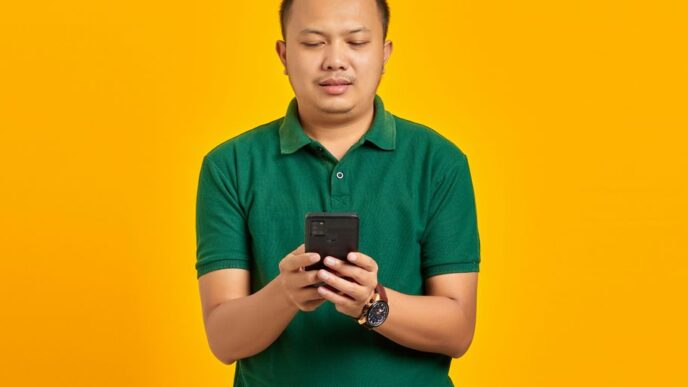 a man in a green shirt looking at a cell phone