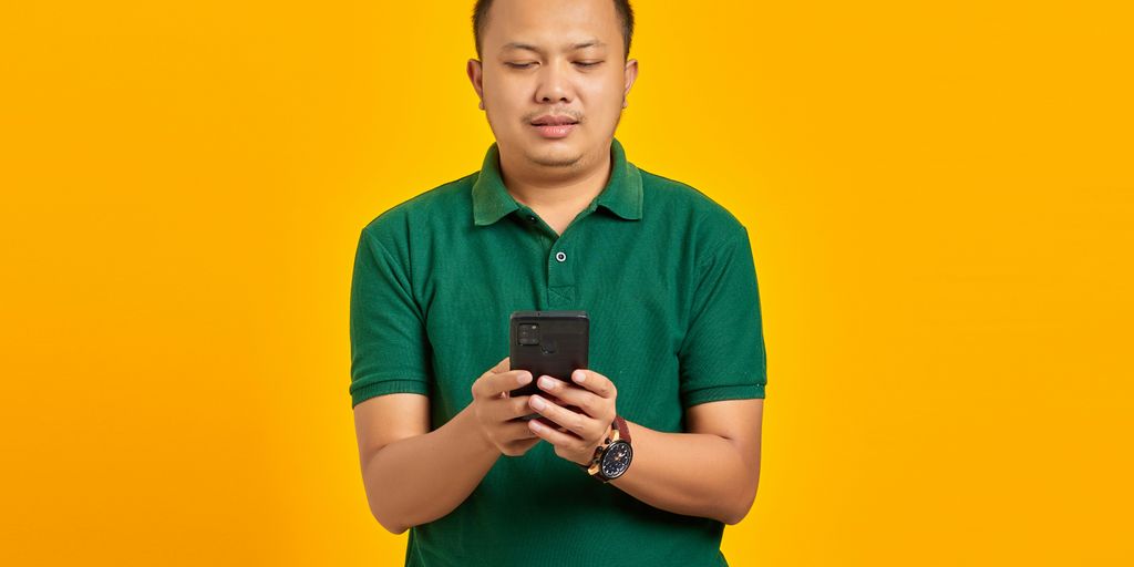 a man in a green shirt looking at a cell phone