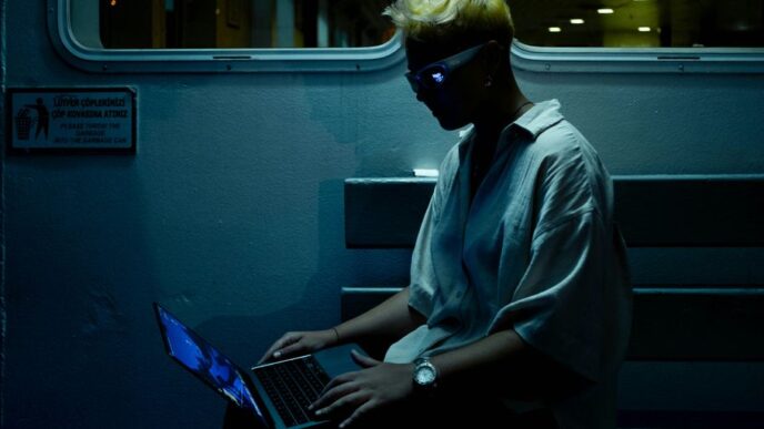 A man sitting on a train using a laptop computer
