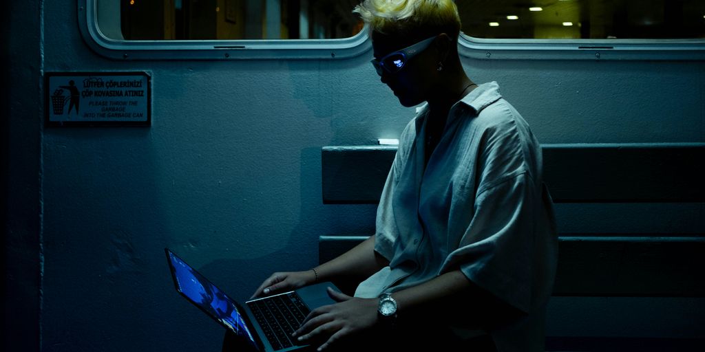 A man sitting on a train using a laptop computer