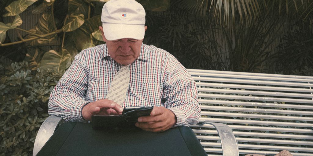 a man sitting on a bench looking at his cell phone
