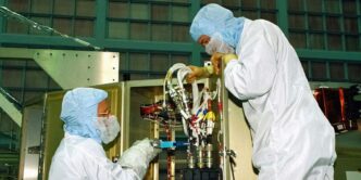 a couple of people in white suits working on a machine