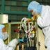 a couple of people in white suits working on a machine