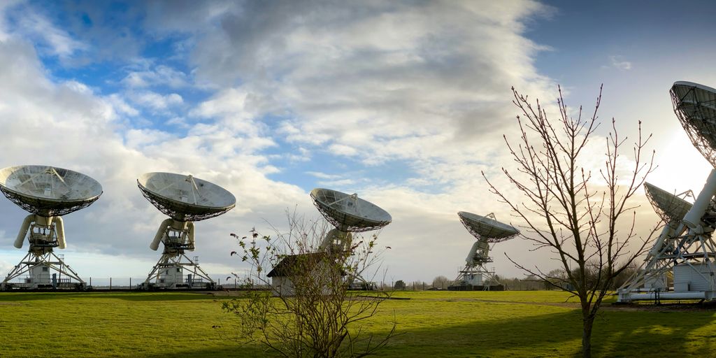 white satellite dish on green grass field under blue sky and white clouds during daytime