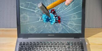a person holding a pencil and a broken laptop