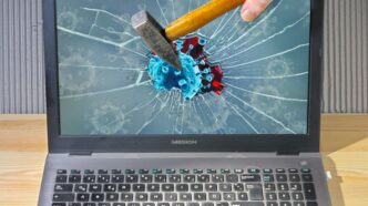 a person holding a pencil and a broken laptop