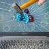 a person holding a pencil and a broken laptop