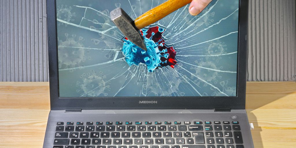 a person holding a pencil and a broken laptop