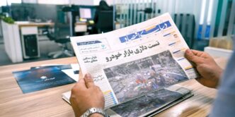 a man sitting at a table reading a newspaper