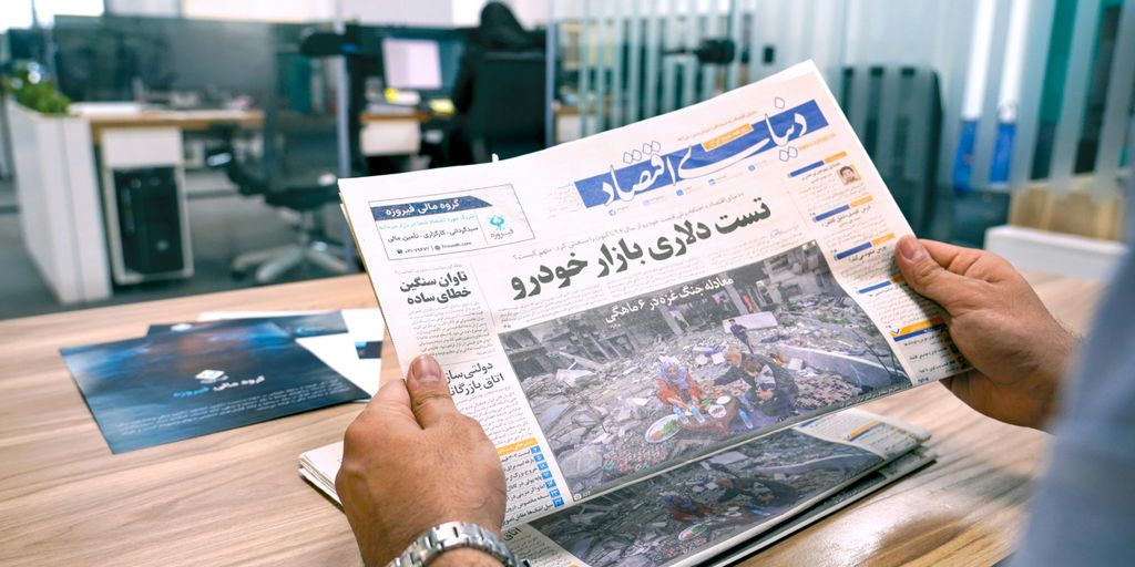 a man sitting at a table reading a newspaper
