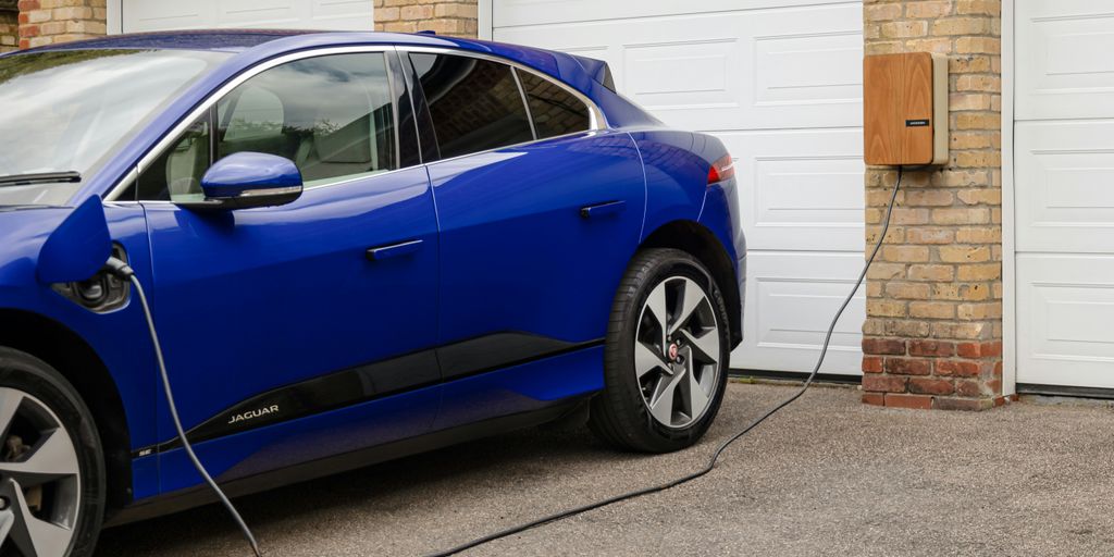 A blue electric car plugged in to a garage