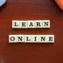 a wooden table with scrabble tiles spelling learn online