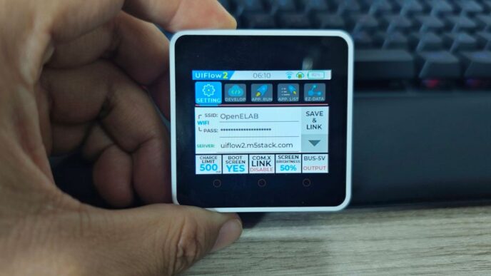 A hand holds a small device showing data.