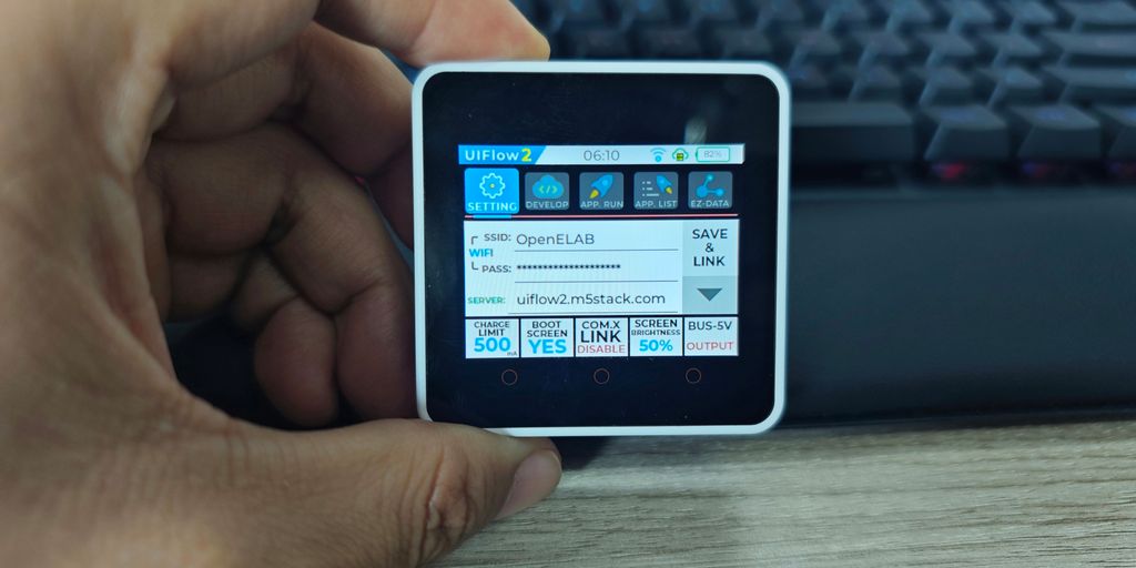 A hand holds a small device showing data.