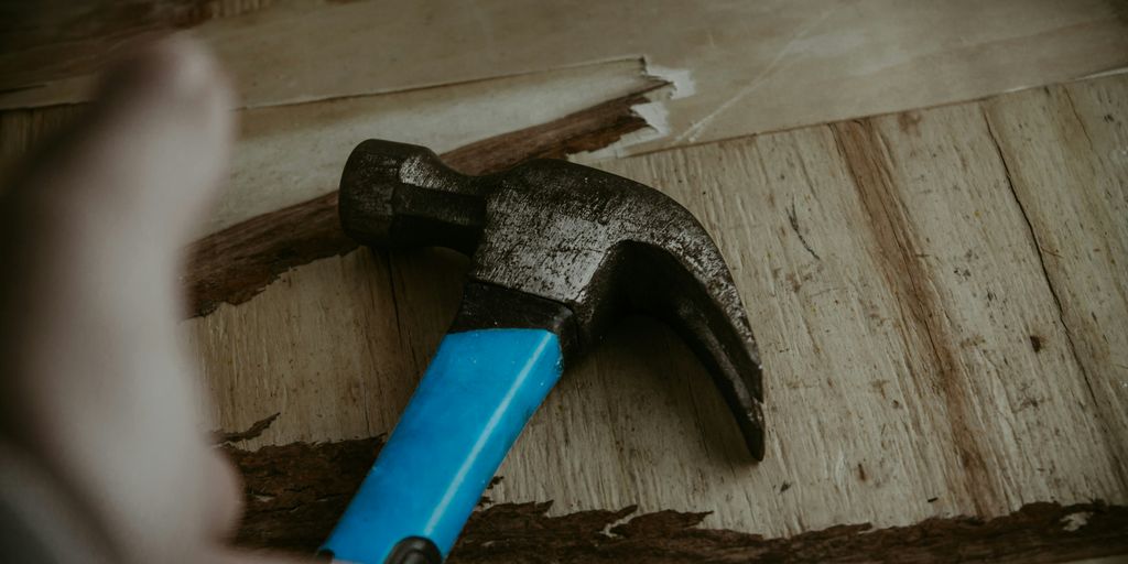a hammer with a blue handle on a piece of wood