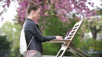 girl in black jacket and pink pants standing on white chair
