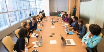 people sitting beside rectangular brown table with laptops