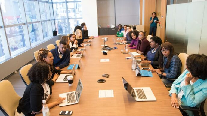 people sitting beside rectangular brown table with laptops