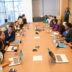 people sitting beside rectangular brown table with laptops