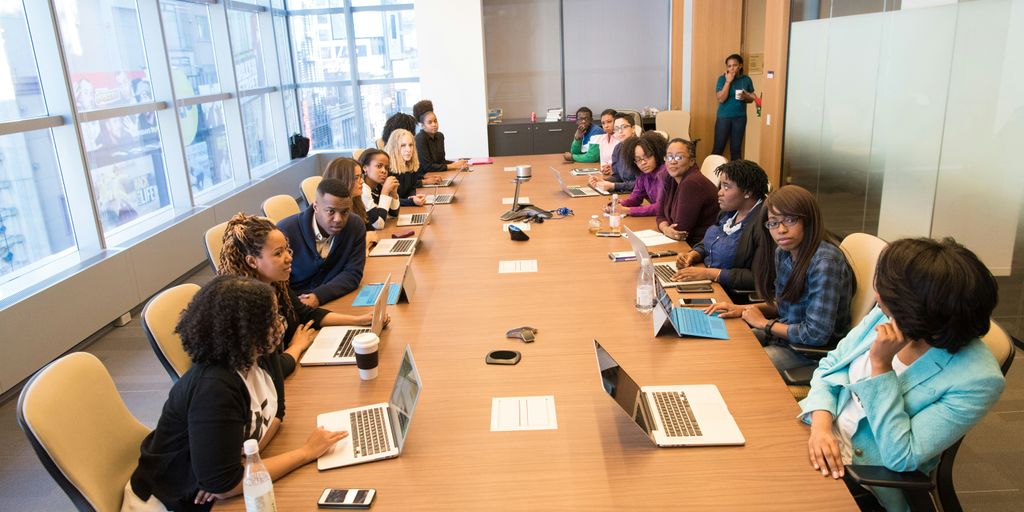 people sitting beside rectangular brown table with laptops