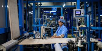 A factory worker operates textile machinery.