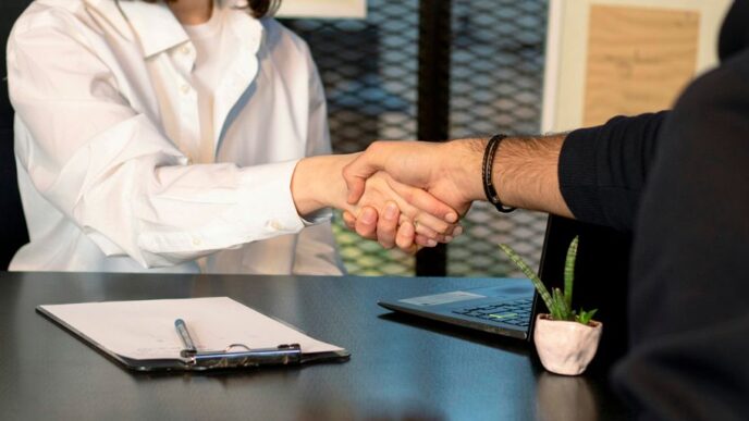 a man and a woman shaking hands in front of a laptop