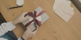 a person opening a gift box with a red ribbon
