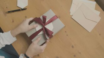 a person opening a gift box with a red ribbon