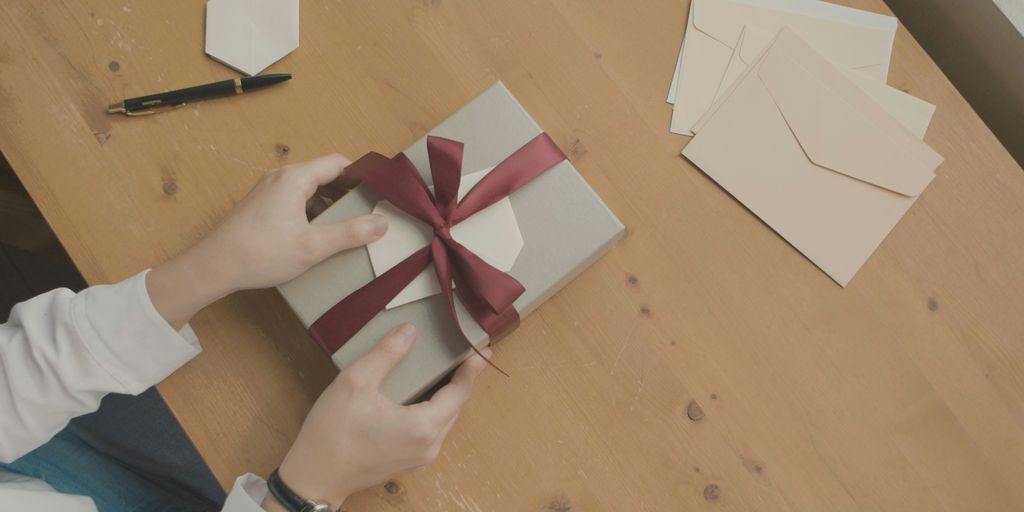a person opening a gift box with a red ribbon