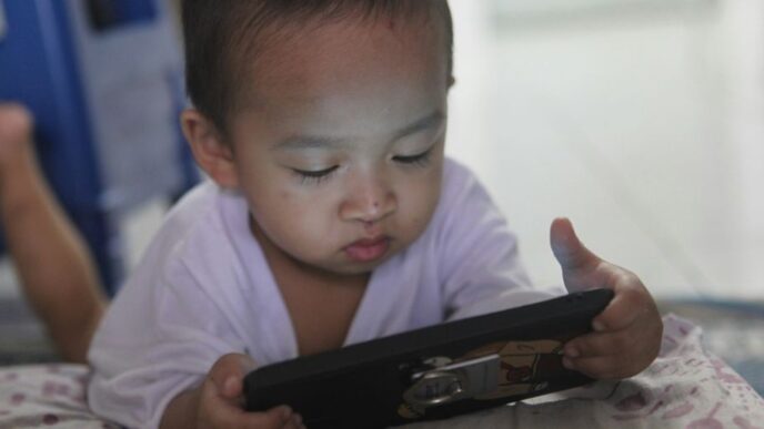 a small child laying on a bed playing with a tablet