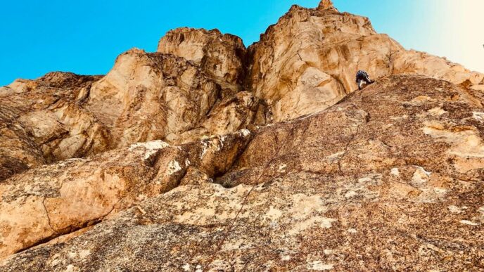 person climbing on rocky mountain during daytime