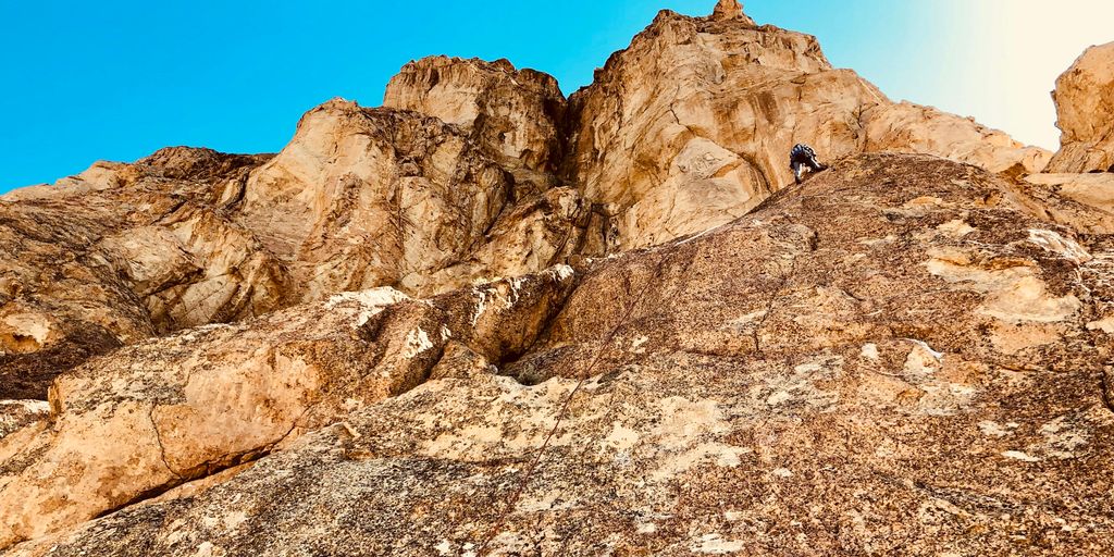 person climbing on rocky mountain during daytime