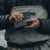 person in black jacket holding black smartphone