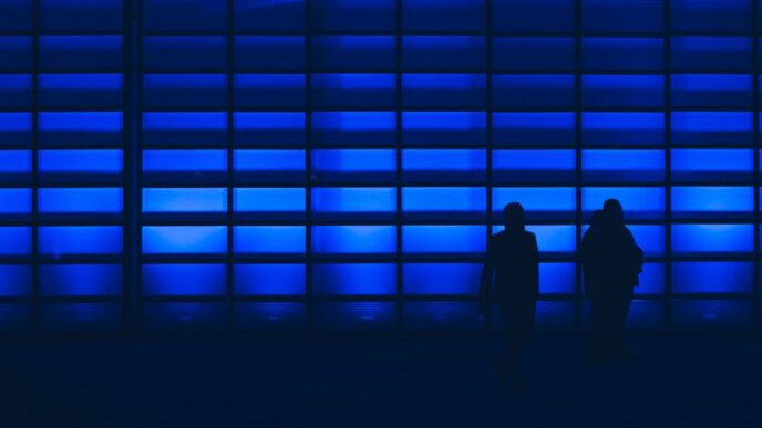 silhouette photo of two person standing near wall