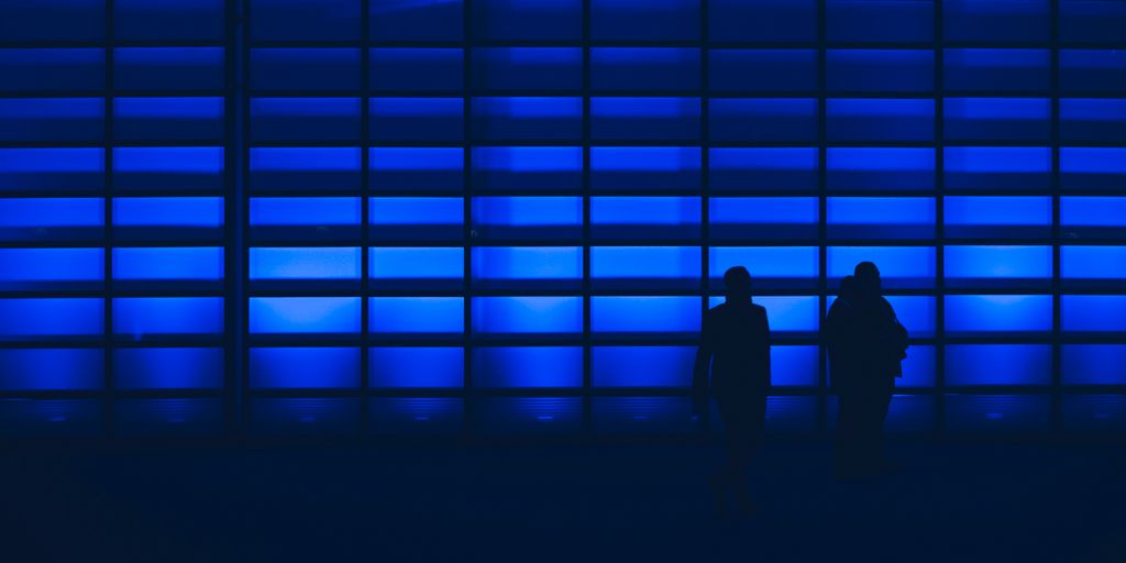 silhouette photo of two person standing near wall