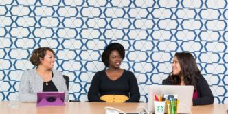 three women sitting on chairs front of table