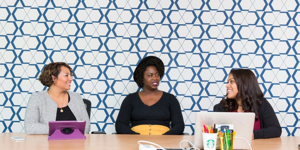 three women sitting on chairs front of table