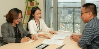 man and two women sitting beside brown wooden table close-up photography