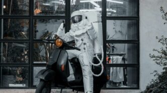 Astronaut rides a scooter in front of a window.