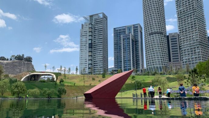 people near green field beside tall and high-rise building under blue and white skies