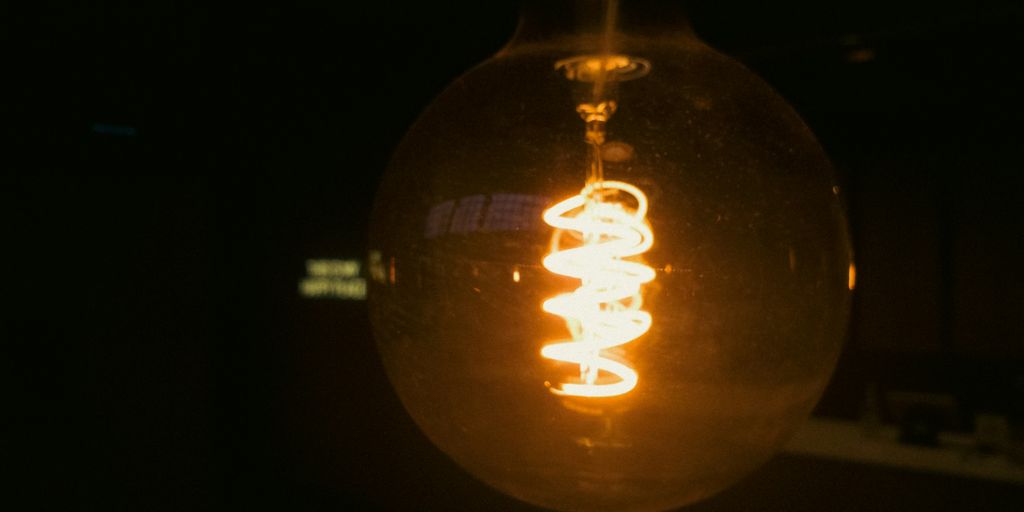 A lightbulb illuminates a dark background.